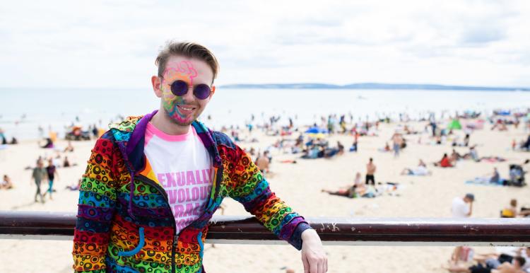 Man wearing a multicoloured hoodie and colourful face paints