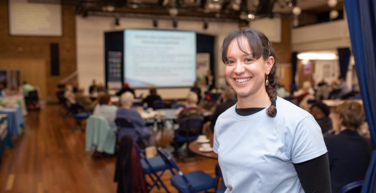 Woman smiling at the camera in a busy indoor event