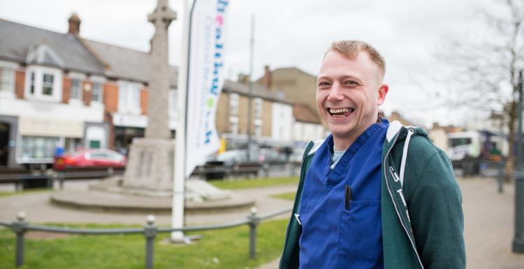 Man in scrubs in front of a Healthwatch banner