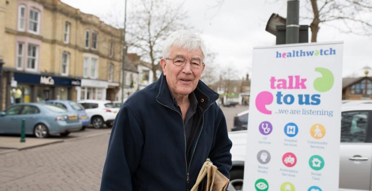 Man standing in front of a Healthwatch banner