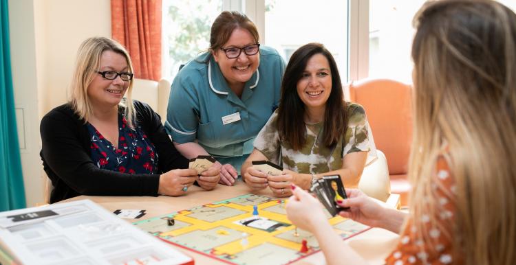 Two women and a nurse sitting round a table playing games