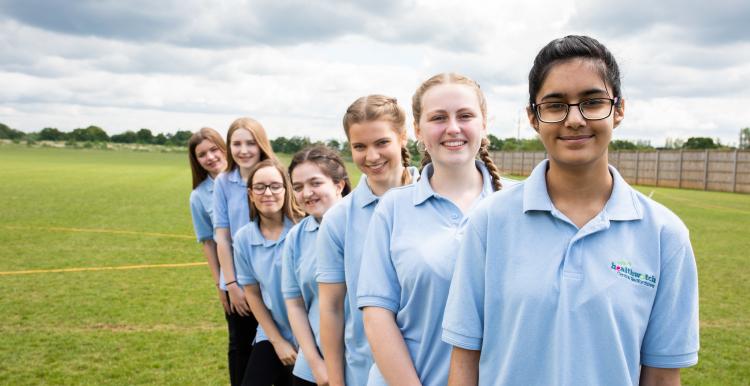 Seven young girls in a row on a school playing field