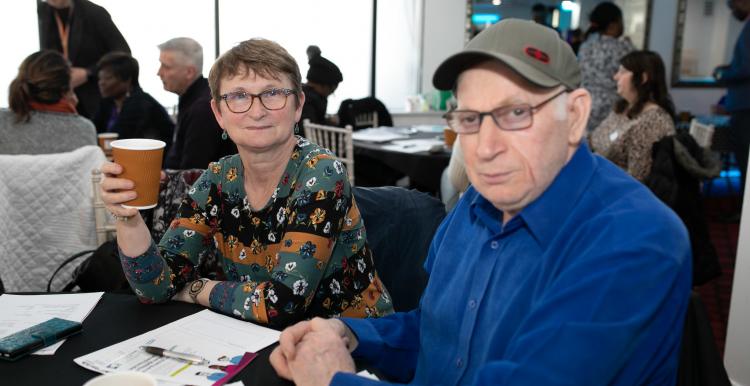 Two people sat at a table drinking coffee in a crowded room