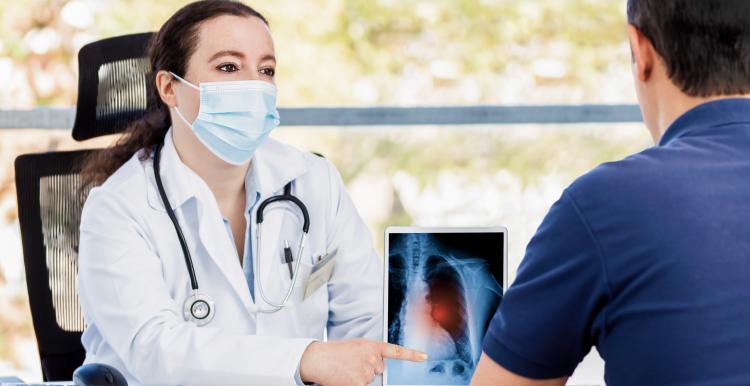 Female doctor showing a patient their x-ray results on a digital screen