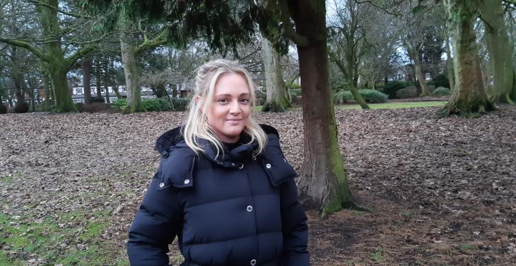 Ashley, a young white woman with blonde hair, standing in a wood