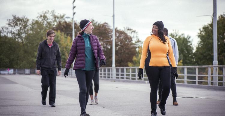A group of mixed age people, including older people, walking down a road. They are dressed for cold weather.