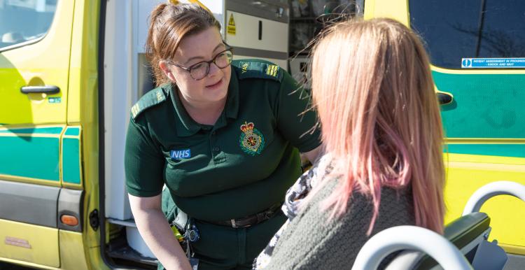 paramedic outside of an ambulance talking to a patient