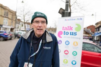 Male volunteer standing in front of a banner "Talk to us" 