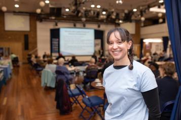 Woman smiling at the camera in a busy indoor event