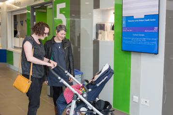 Two women smiling down at a baby in a pushchair