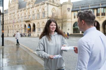 Teenage girl giving a leaflet to someone