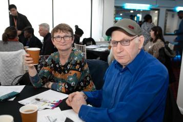 Two people sat at a table drinking coffee in a crowded room