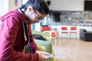 Young person in a empty GP waiting room looking at her phone