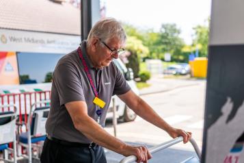 Grey-haired volunteer pushes a trolley outside a hospital