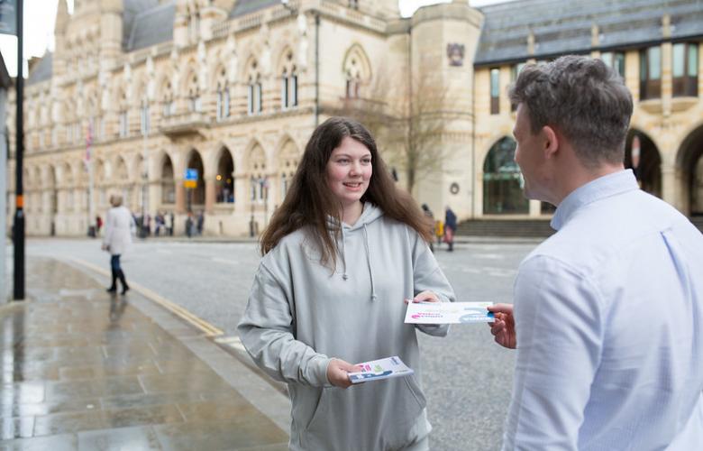 Teenage girl giving a leaflet to someone